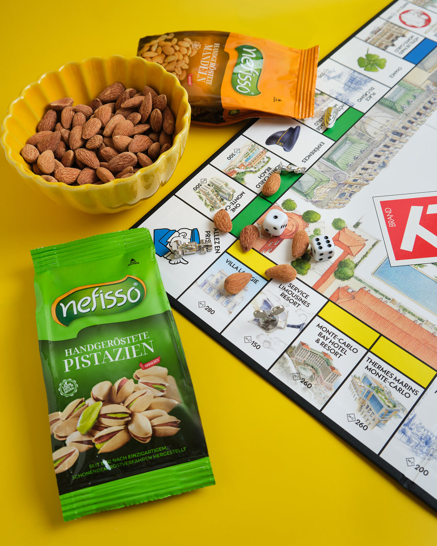 Nefisso Pistazien und Mandeln mit Nüssen und einem Brettspiel auf gelbem Tisch